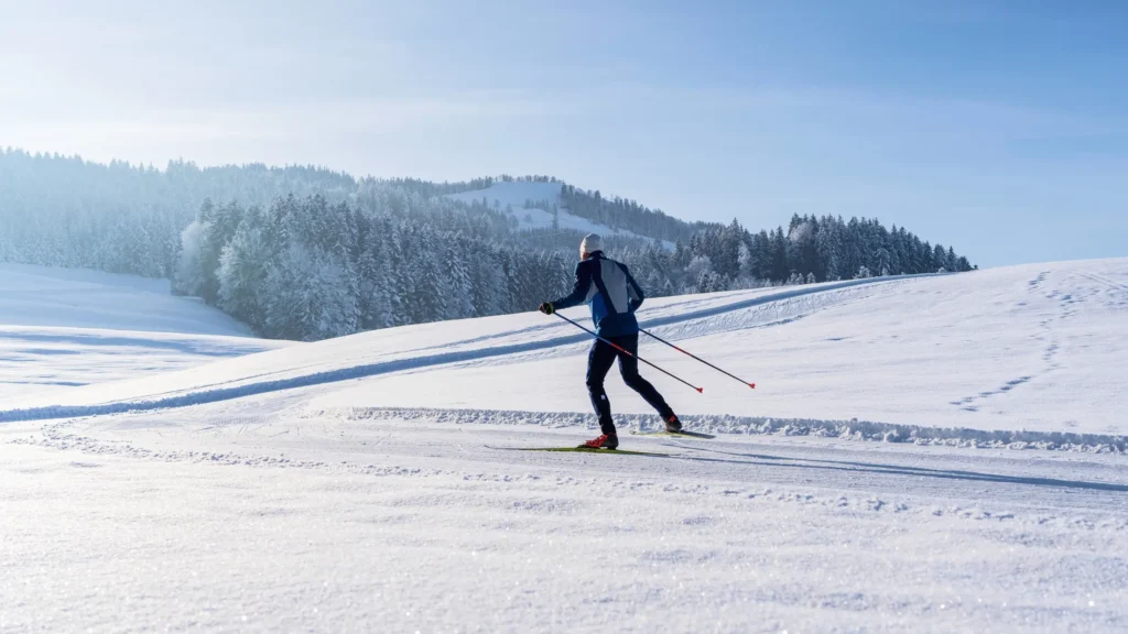 Langläufer in der klassischen Spur vor verschneiten Appenzeller Hügeln